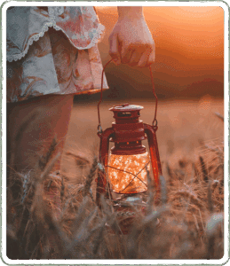 Figure holds a lantern in a wheat field at sunset, warm light and rich colors creating a calm, reflective atmosphere!