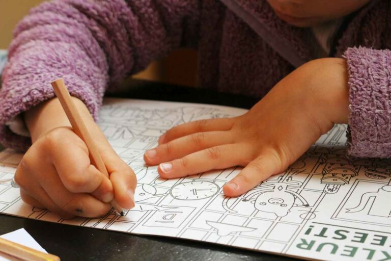 Close-up of a child coloring a worksheet, symbolizing learning and evaluation in school and private settings.