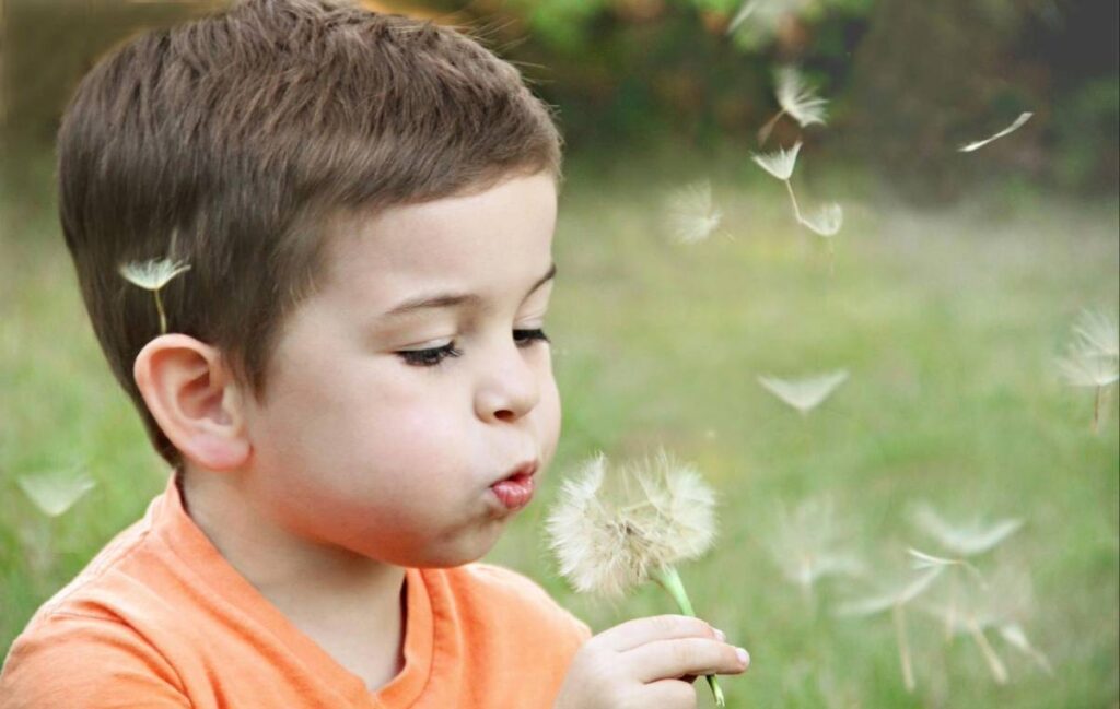 Child blowing on a dandelion, symbolizing autism masking and hidden struggles