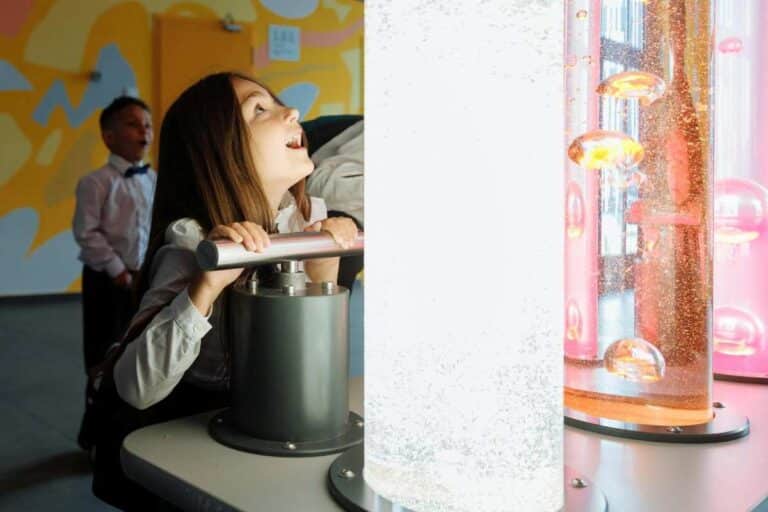 Child exploring sensory lights in an interactive exhibit, showing how sensory processing affects behavior and learning.