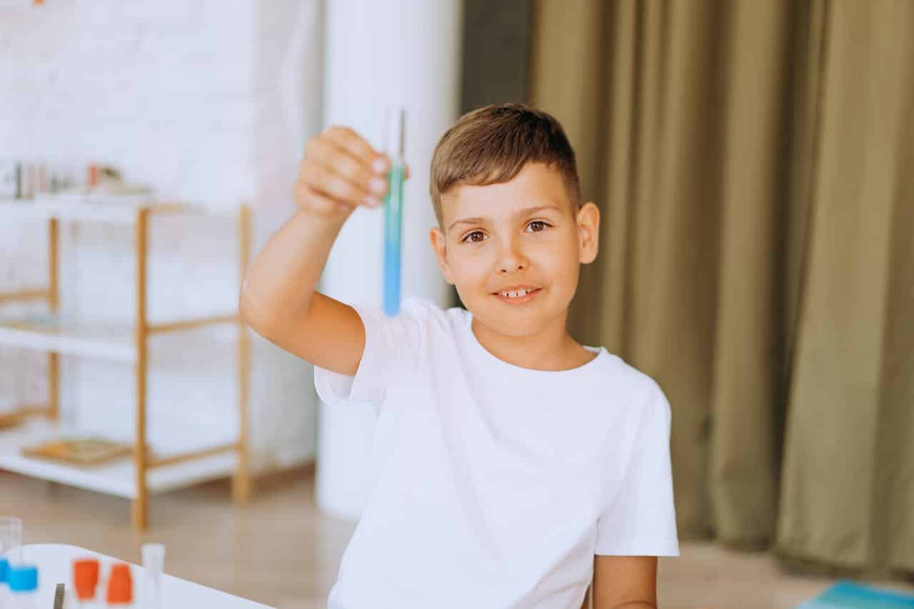 Child holding a test tube during a science activity, illustrating focus and curiosity often compared when evaluating ADHD vs typical childhood energy.