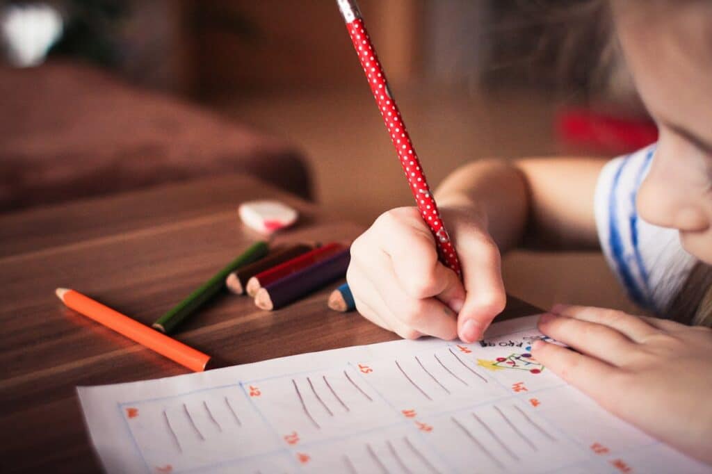Child concentrating while writing on a worksheet at home, representing attention and focus patterns discussed when identifying ADHD in children.