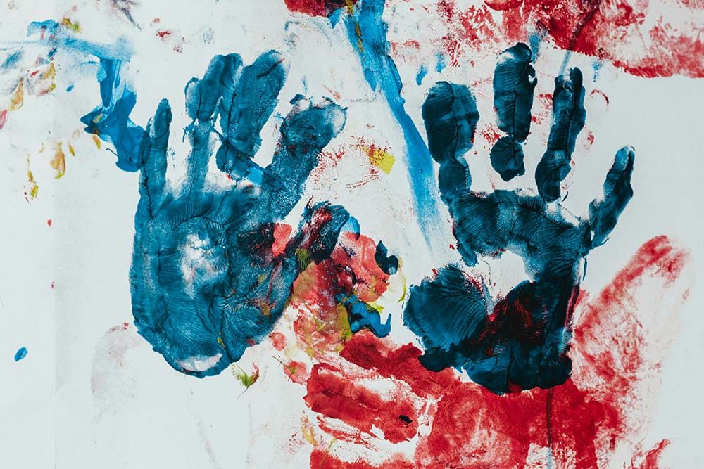 Painting of colorful handprints on a surface.